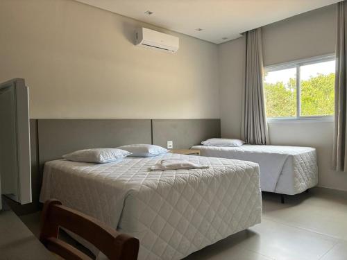 a bedroom with two beds and a window at Hotel São Francisco in Itaí