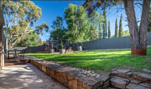 a yard with a stone retaining wall and a bench at Relaxing Family Retreat with Outdoor Entertaining in Golden Square