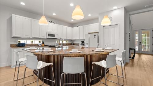 a kitchen with a large island with white chairs at 6BR Luxury Home with Private Pool and BBQ in Kissimmee