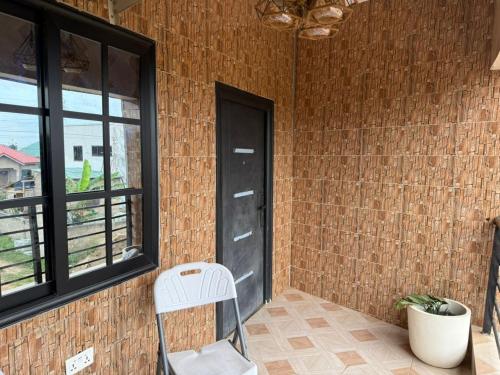 a white chair sitting next to a brick wall with a door at Jayda Lodge in Kwedonu