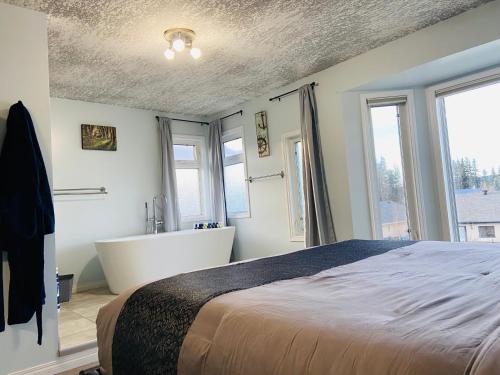 a bedroom with a bed and a bath tub and windows at A beautiful 2 bedroom private home in Hinton