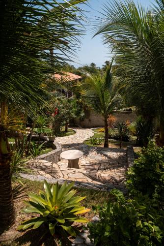 a garden with a table and palm trees at Pipa Golfinhos Pousada in Pipa