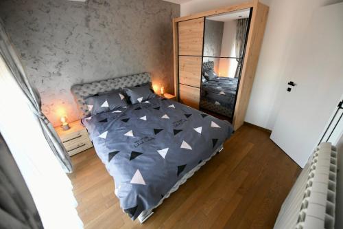 a bedroom with a bed with a gray comforter and a mirror at Cristal Palace Suites 003 in Kragujevac