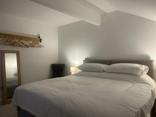 a bedroom with a bed with white sheets and pillows at Richmond, Keswick town centre apartment in Keswick