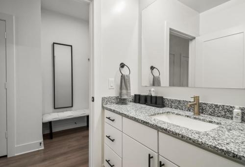 a white bathroom with a sink and a mirror at Stylish New Studio DT - Pool, Gym - Rooftop Lounge in Houston