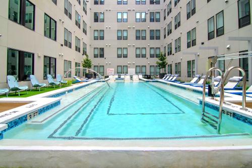 a large swimming pool with chairs and a building at Stylish New Studio DT - Pool, Gym - Rooftop Lounge in Houston