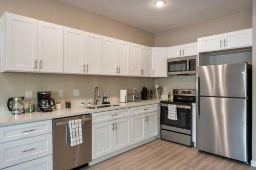 a kitchen with white cabinets and a stainless steel refrigerator at Cozy Cactus - 5 Bed Suite w Pool - Stadium - Golf in Surprise