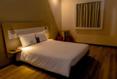 a bedroom with a large bed with white sheets and pillows at Ibis Budget Lorena - Circuito da Fé in Lorena