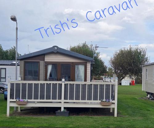 a tiny house with a sign that reads tritzs caravan at Trish's Caravan Coop 144 in Kinmel Bay