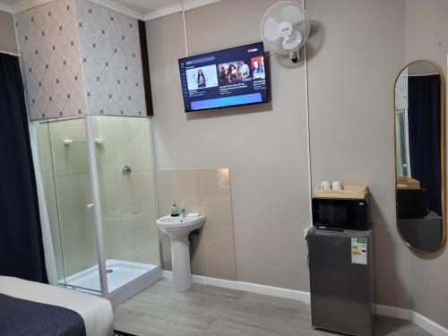 a bathroom with a shower toilet and a tv on the wall at Prime Executive Accommodation in Cape Town