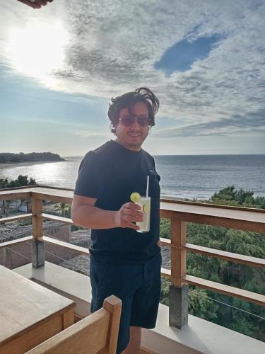 a man standing on a balcony holding a drink at PUNTA VELEROS ROOFTOP in Los Órganos
