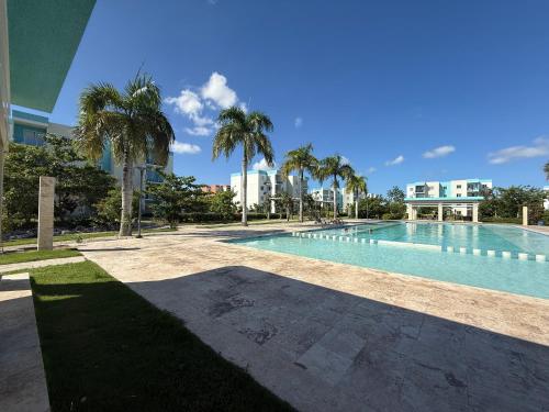 a swimming pool with palm trees next to a building at Your Crissere Tropical Dream RD in Punta Cana