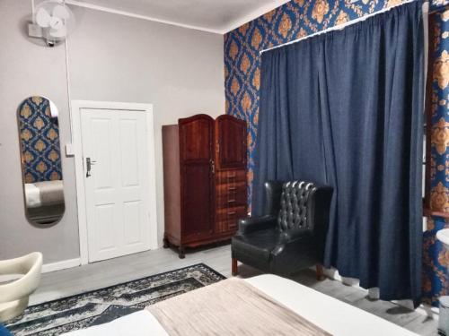 a bedroom with a bed and a chair and a mirror at Prime Executive Accommodation in Cape Town