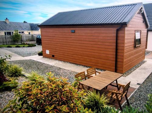 a wooden building with a wooden table and benches at Chata in Stornoway