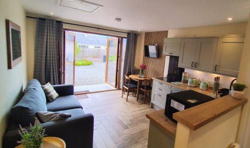 a living room with a blue couch and a kitchen at Chata in Stornoway