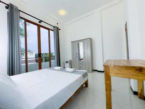 a white bedroom with a bed and a desk at Calm & Unic in Ja-Ela