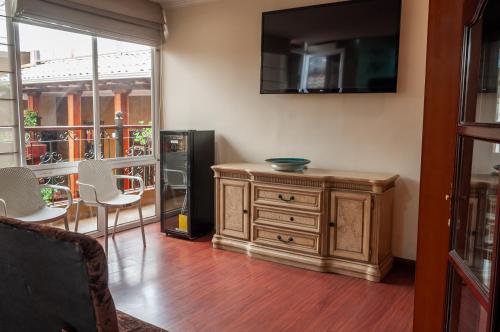 a living room with a wooden cabinet and a television at Hotel Campanario in Cuenca