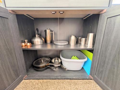 a cabinet filled with pots and pans and a bowl at Gateway Glamping in Gateway