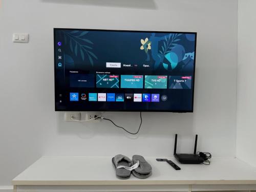 a flat screen tv hanging on a wall with shoes at Spacious 1 Bedroom, with sofa bed and Balcony in Kathu