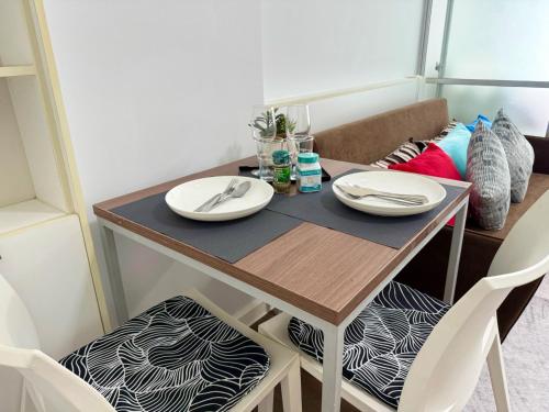 a small dining room table with two white plates on it at Spacious 1 Bedroom, with sofa bed and Balcony in Kathu