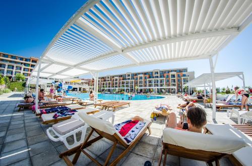 a group of people sitting in lounge chairs by a pool at Premier Fort Beach Resort in Sunny Beach