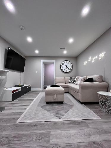 a living room with a couch and a clock on the wall at Modern Suite in Etobicoke - Near Airport & Downtown! in Toronto