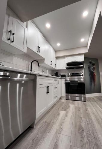 a kitchen with white cabinets and stainless steel appliances at Modern Suite in Etobicoke - Near Airport & Downtown! in Toronto
