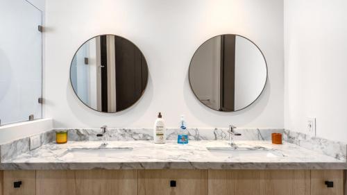 a bathroom with two sinks and two mirrors at Stunning 2BR Condo - 5 Min to Beach in Cabo San Lucas