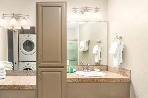 a bathroom with a sink and a washing machine at Banyan Harbor Resort in Lihue
