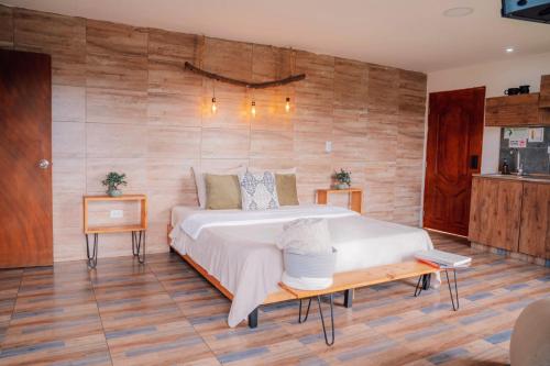 a bedroom with a large bed and wooden walls at Cabañas con jacuzzi y chimenea - Casa Floral, Marinilla in Marinilla