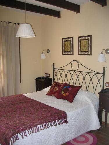 a bedroom with a large bed with a red pillow at Hotel de Montaña Cueva Ahumada in Villaverde de Guadalimar