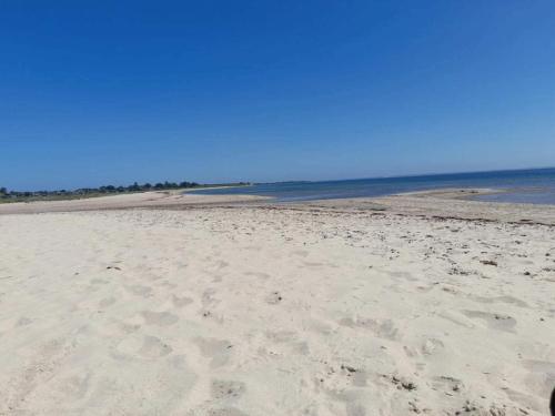a beach with footprints in the sand and the ocean at 4 person holiday home in Haderslev in Haderslev