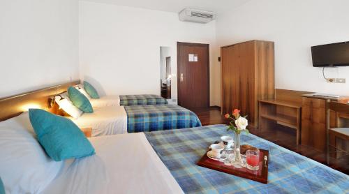 a hotel room with two beds and a television at Hotel Ristorante Dante in Torgiano