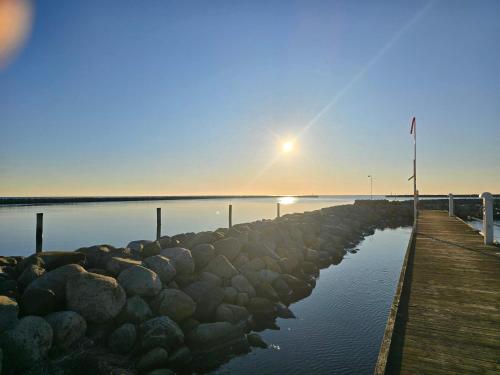 a dock with rocks in the water at sunset at 5 person holiday home in Karrebæksminde in Karrebæksminde