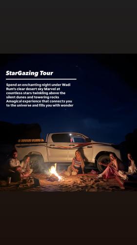 a group of people sitting around a fire next to a truck at Redsand Valley Retreat in Disah