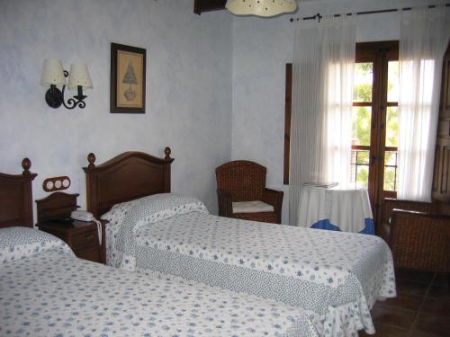 a bedroom with two beds and a window at Hotel de Montaña Cueva Ahumada in Villaverde de Guadalimar