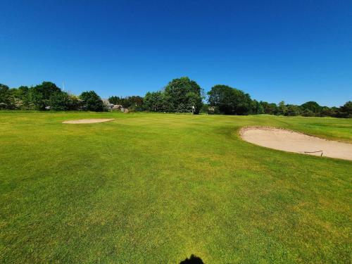 a golf course with a green field and a dirt road at 4 star holiday home in Ørsted-By Traum in Ørsted
