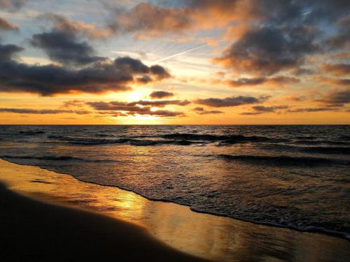 a sunset on the beach with the ocean at 6 person holiday home in Pandrup-By Traum in Pandrup