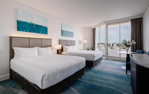 a hotel room with two beds and a balcony at Rendezvous Hotel Perth Scarborough in Perth
