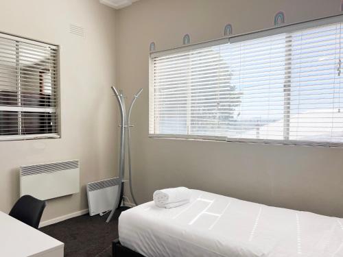 a bedroom with a white bed and a window at Cheerful 3-bedroom home with free parking on site in Wagga Wagga