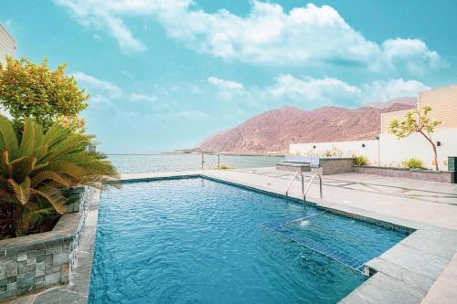 a swimming pool with a view of the water at Montagne 1 Luxury Villa 4 BR - Al Dana Island Fujairah in Fujairah