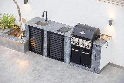 an outdoor kitchen with a grill and a sink at Montagne 1 Luxury Villa 4 BR - Al Dana Island Fujairah in Fujairah