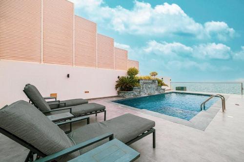 a swimming pool with chaises and chairs next to a building at Montagne 1 Luxury Villa 4 BR - Al Dana Island Fujairah in Fujairah