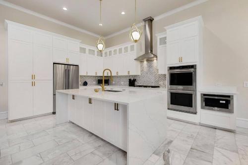 a kitchen with white cabinets and a large island at Luxury Oak Lawn Home | Game Room, Parking, Balcony in Dallas