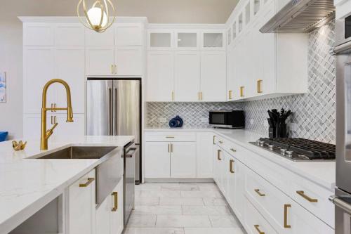 a white kitchen with a sink and a refrigerator at Luxury Oak Lawn Home | Game Room, Parking, Balcony in Dallas