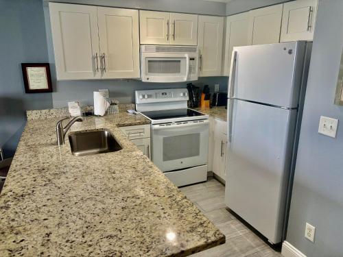 a kitchen with a white refrigerator and a sink at Ocean Walk Resort - Spectacular Ocean Front View in Daytona Beach