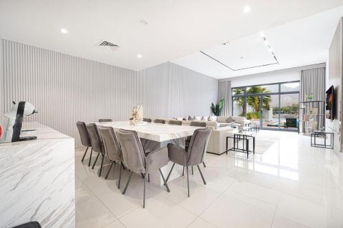 a white dining room with a table and chairs at The Wave Villa - Al Dana Island Fujairah in Fujairah