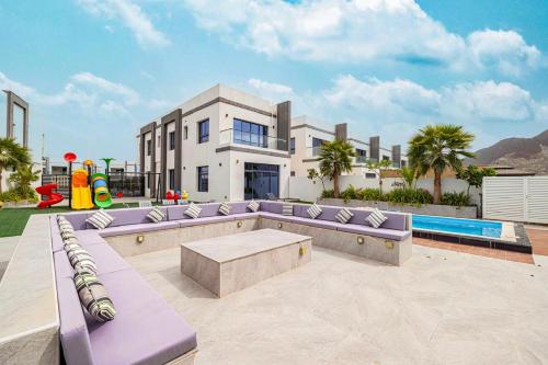 a house with purple furniture and a swimming pool at The Wave Villa - Al Dana Island Fujairah in Fujairah