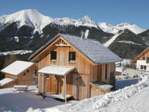 a wooden cabin in the snow with snow covered mountains at Die Bergliebe in Hohentauern