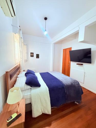 a bedroom with a bed with blue pillows and a tv at MAKTVB Europa - Hostal Boutique in Santiago